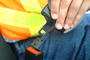 Motorist buckling their seat belt.